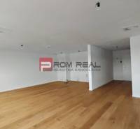 Ein geräumiges Zimmer mit Holzboden in einer 4-Zimmer-Wohnung, helle Wände und eine einfache Einrichtung.