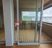 Glastüren führen auf die Loggia in einer 4-Zimmer-Wohnung mit Blick auf die Hügel.