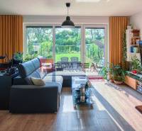 Wohnzimmer in einem Einfamilienhaus mit Kamin, Sofa und verglasten Türen zum Garten.