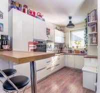 Eine Küche in einem Einfamilienhaus mit weißen Möbeln, einer Bar und einer Kaffeemaschine.