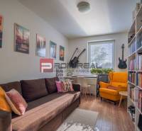 Wohnzimmer in einem Einfamilienhaus mit Sofa, Bücherregalen und Musikinstrumenten.
