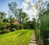 Der Garten eines Einfamilienhauses in Slovenský Grob mit gepflegtem Rasen und Gehweg.