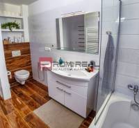 Badezimmer in einem Einfamilienhaus mit Badewanne, Waschbecken und Toilette, Holzboden.