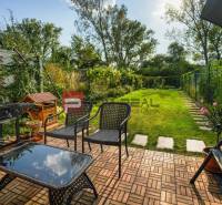 Der Garten eines Einfamilienhauses in Slovenský Grob mit Terrasse, Grill und Rasen.
