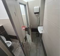 Toilette in Geschäftsräumen mit Waschbecken und Papierhandtuchspender.