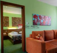 Das Innere der Pension mit einem orangefarbenen Sofa, Bildern und einem Bett mit bunten Decken.