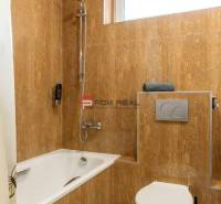 Badezimmer mit Badewanne und Toilette in Hotels und Pensionen, gefliest mit braunen Fliesen.