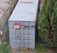 An der Púchovská-Straße in Bratislava III befindet sich ein Schiffscontainer neben Grünflächen und einem Zaun.