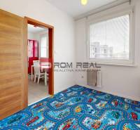 Kinderzimmer in einer 4-Zimmer-Wohnung mit blauem Teppich und Blick aus dem Fenster.