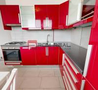 Rote Küche in einer 4-Zimmer-Wohnung mit Gasherd und weißem Tisch.
