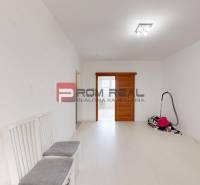 Ein heller Raum in einer 4-Zimmer-Wohnung mit Schiebetüren und Stühlen. Ein abgestellter Staubsauger auf dem Boden.