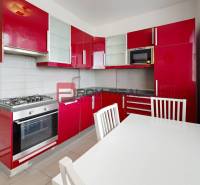 Küche mit roten Schränken und Gasherd in einer Vierzimmerwohnung.