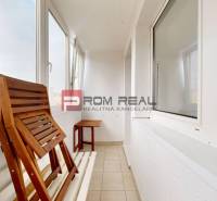 Verglaster Balkon einer 4-Zimmer-Wohnung mit Holzmöbeln und Blick auf die Stadt.