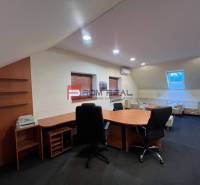 Büro von Produktionsräumen mit Stühlen und Tisch, beleuchtet mit künstlichem Licht.