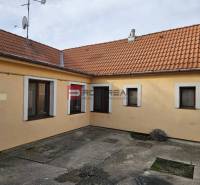 Der Hof des Einfamilienhauses in der Sonnenstraße in Pezinok mit Betonpflaster und orangefarbener Fassade.