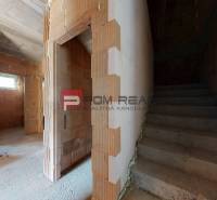 Rohbau in einem Einfamilienhaus mit Treppe und Ziegelwänden.