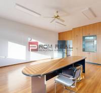 Büros mit Holzmöbeln und Tisch, geräumiges Interieur, Fenster, Deckenventilator.