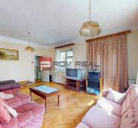 Wohnzimmer in einem Einfamilienhaus mit hellen Wänden, Sofa und Fernseher.