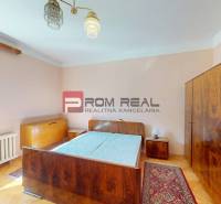Schlafzimmer in einem Einfamilienhaus mit antiken Möbeln, Holzboden und großem Fenster.