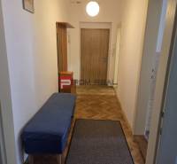Der Flur mit einer blauen Bank und Holztüren, der eine 2-Zimmer-Wohnung einrichtet.