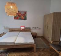 Schlafzimmer in einer 2-Zimmer-Wohnung mit Holzmöbeln, Kronleuchtern und einem Blumenbild.