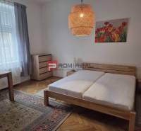 Schlafzimmer mit einem Holzbett, einem Schreibtisch und heller Dekoration in einer 2-Zimmer-Wohnung.
