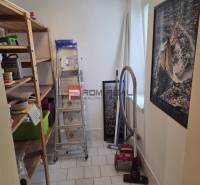 Stauraum in einer 2-Zimmer-Wohnung mit Regalen, Staubsauger und Leiter.