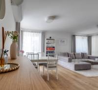 Helle Innenausstattung einer 3-Zimmer-Wohnung mit Sofa, Essbereich und Dekorationen auf einem Holztisch.