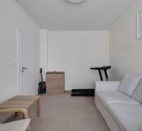 Ein Zimmer in einer 3-Zimmer-Wohnung mit einem weißen Sofa, einer Gitarre und einem Laufband.
