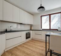Küche in einer 3-Zimmer-Wohnung mit Holzboden und weißen Schränken.