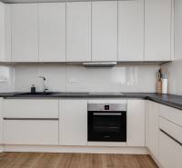 Küche in einer 3-Zimmer-Wohnung mit weißen Schränken und dunkler Arbeitsplatte.