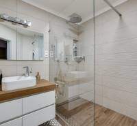 Badezimmer mit weißem Waschbecken auf einer Holzplatte und großem Spiegel, 3-Zimmer-Wohnung.