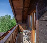 Balkon mit Tisch und Stühlen in einer Ferienwohnung mit Blick auf die Bäume in der Hohen Tatra.