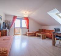 Ferienwohnung mit orangefarbenem Sofa und Esstisch unter dem Dachfenster.