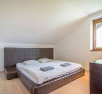 Schlafzimmer in einer Ferienwohnung mit Doppelbett, Fenster, Holzmöbeln und Dachschrägen.