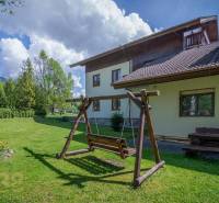 Garten mit einer Holzschaukel und einer Bank beim Ferienapartment in der Hohen Tatra.