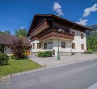 Ferienwohnung in der Hohen Tatra, umgeben von Grün, blauer Himmel, Berge im Hintergrund.