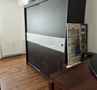 Schrank mit Schiebetüren und Dekorationen, Holzboden in einer 2-Zimmer-Wohnung.