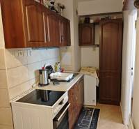 Küche in einer 2-Zimmer-Wohnung mit Herd, Spüle und Holzschränken.