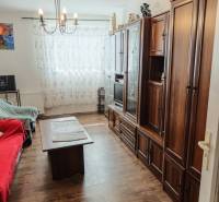 Wohnzimmer mit Holzmöbeln, Sofa und Kronleuchter in einer Zweizimmerwohnung.