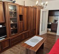 Wohnzimmer mit einer Holzwand-Einheit, einem Kronleuchter und einem Tisch in einer Zweizimmerwohnung.