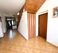 Flur in einem Einfamilienhaus mit Holztreppe, Fliesen und einer Vase mit Blumen an der Wand.