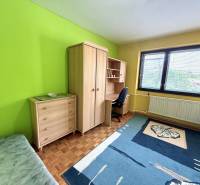 Ein Zimmer in einem Einfamilienhaus mit einer grünen Wand, einem Schrank und einem Schreibtisch.