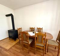 Im Inneren eines Einfamilienhauses sind ein Kaminofen und ein Esstisch mit Holzstühlen zu sehen.