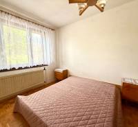 Schlafzimmer mit Bett, Fenster und Holzboden in einem Einfamilienhaus.