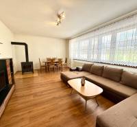 Wohnzimmer in einem Einfamilienhaus mit Kamin, Sofa, Esstisch und Fernseher.