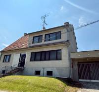 Ein Einfamilienhaus in Koválov mit hellen Fenstern und einer Garage auf einem leicht abfallenden Grundstück.