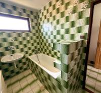Ein Badezimmer in einem Einfamilienhaus mit grünen Fliesen, einer Badewanne und einem Waschbecken.