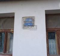 Zwei vernachlässigte Fenster eines Einfamilienhauses in Ladzany mit einem erodierten Schriftzug an der Wand.