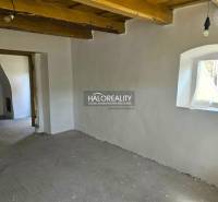 Innenraum eines Einfamilienhauses mit heller Wandfarbe, Holzbalkendecke und kleinem Fenster.